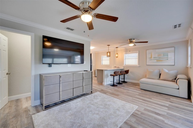 living room featuring light wood finished floors, visible vents, and crown molding