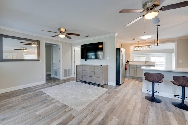 kitchen with freestanding refrigerator, light countertops, crown molding, and light wood finished floors