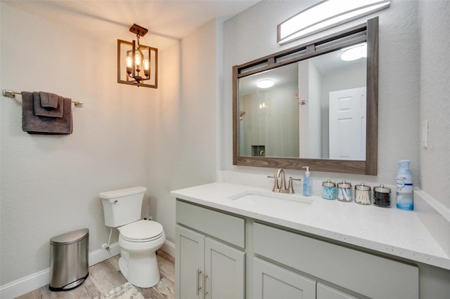 bathroom with toilet, baseboards, wood finished floors, and vanity