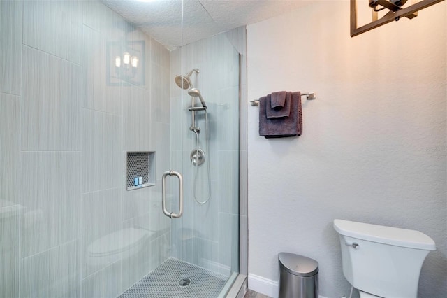 bathroom with a textured ceiling, a shower stall, and toilet