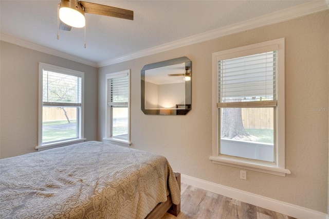 bedroom with baseboards, ornamental molding, ceiling fan, and wood finished floors