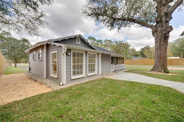 rear view of property featuring fence, a patio, and a lawn