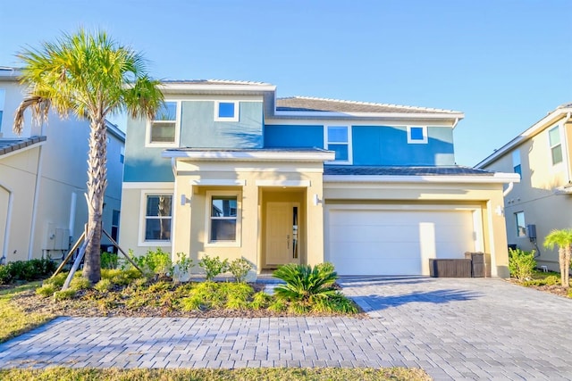 view of front facade featuring an attached garage, decorative driveway, and stucco siding