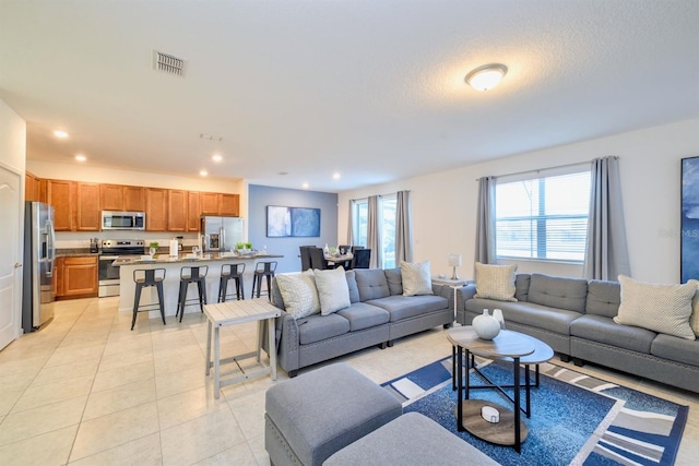 living area with light tile patterned flooring, visible vents, and recessed lighting