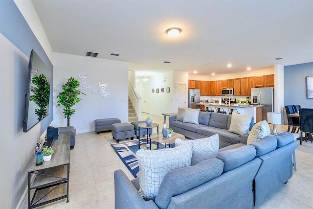 living area with light tile patterned floors, baseboards, visible vents, stairs, and recessed lighting