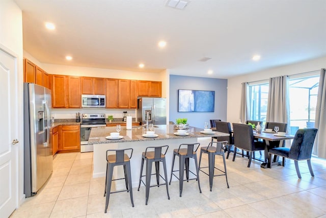 kitchen with visible vents, a kitchen island with sink, stainless steel appliances, a kitchen bar, and recessed lighting