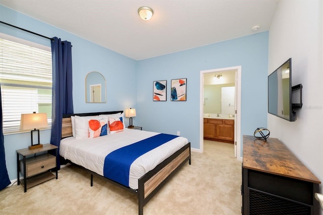 bedroom with light carpet, ensuite bath, baseboards, and a sink