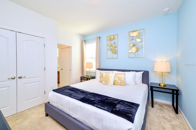 bedroom with a closet, light carpet, and baseboards