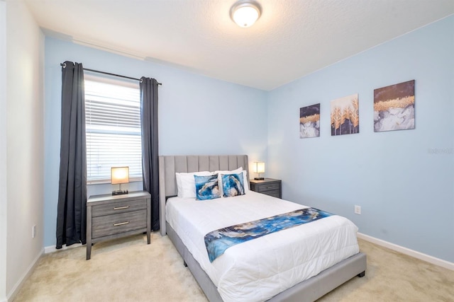 bedroom with light carpet, a textured ceiling, and baseboards