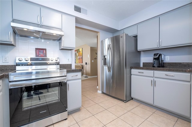 kitchen featuring dark countertops, under cabinet range hood, appliances with stainless steel finishes, and backsplash