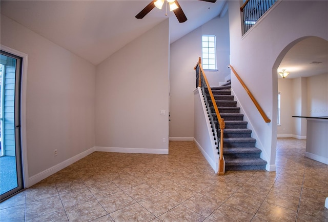 interior space with arched walkways, lofted ceiling, stairway, ceiling fan, and baseboards