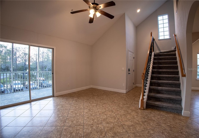 unfurnished living room featuring high vaulted ceiling, ceiling fan, stairs, and baseboards