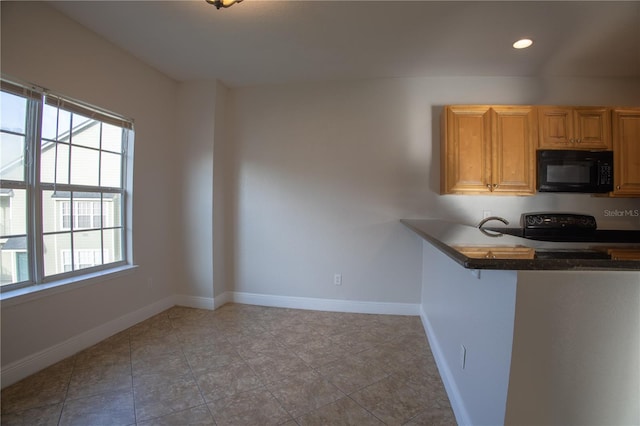 kitchen featuring dark countertops, black microwave, baseboards, and stove