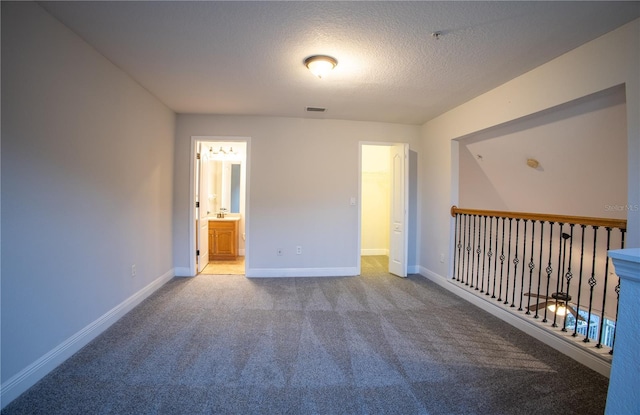 carpeted empty room featuring visible vents, baseboards, and a textured ceiling