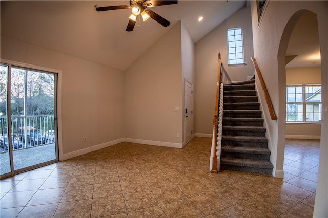 interior space featuring ceiling fan, high vaulted ceiling, arched walkways, and baseboards