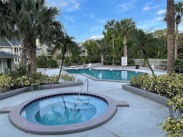 community pool featuring a community hot tub, a patio, and fence