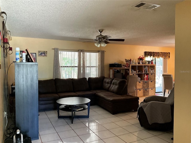 living room with ceiling fan, visible vents, a textured ceiling, and light tile patterned flooring