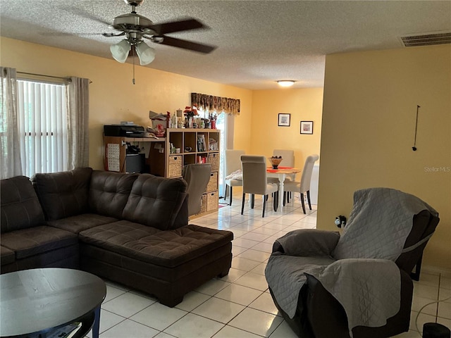 living area with light tile patterned floors, ceiling fan, visible vents, and a textured ceiling