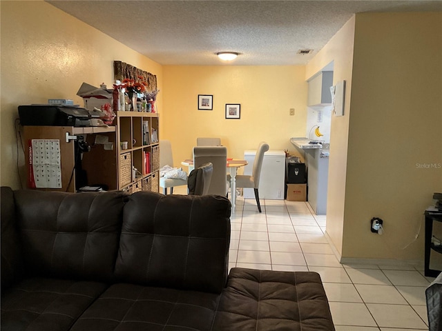 living area with tile patterned flooring, visible vents, and a textured ceiling