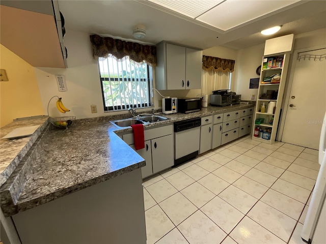 kitchen featuring light tile patterned floors, a sink, dishwasher, stainless steel microwave, and dark countertops