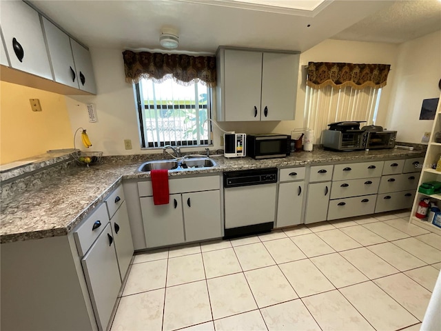 kitchen featuring dark countertops, white dishwasher, a sink, and light tile patterned flooring