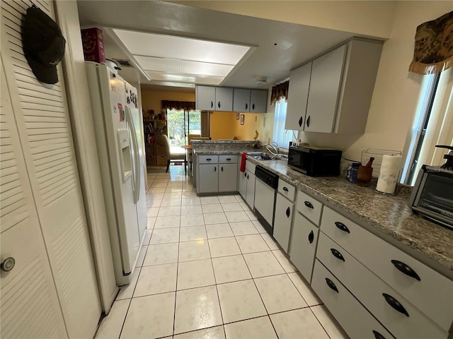 kitchen featuring white appliances, light tile patterned flooring, a sink, and gray cabinetry