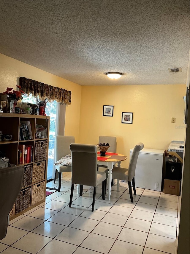 dining room with light tile patterned floors, a textured ceiling, and visible vents