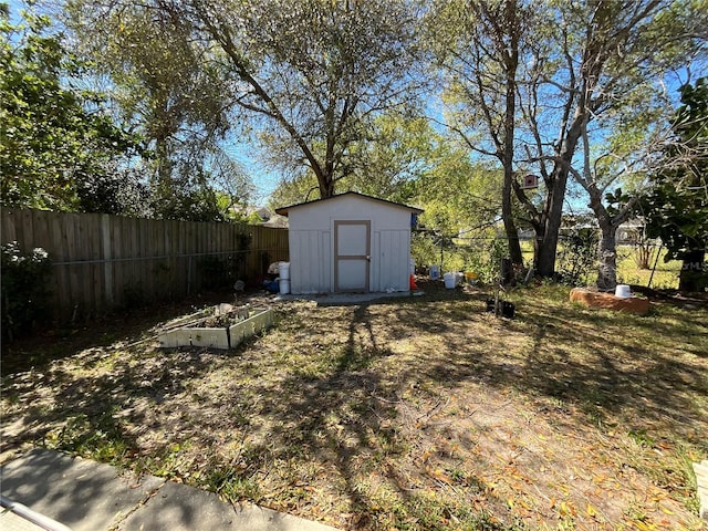 view of yard with fence private yard, a shed, a garden, and an outbuilding