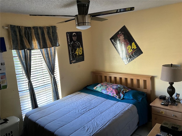 bedroom featuring a ceiling fan, multiple windows, and a textured ceiling