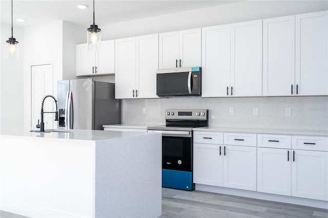 kitchen featuring light wood-type flooring, appliances with stainless steel finishes, backsplash, and hanging light fixtures