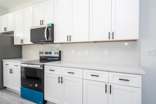 kitchen featuring light wood finished floors, appliances with stainless steel finishes, decorative backsplash, and white cabinets