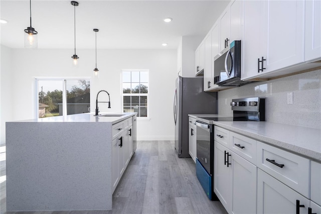 kitchen featuring appliances with stainless steel finishes, a wealth of natural light, a sink, and backsplash