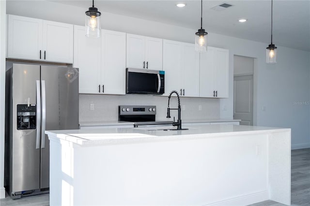 kitchen featuring a center island with sink, visible vents, decorative backsplash, appliances with stainless steel finishes, and light countertops