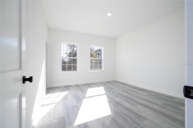 spare room with baseboards, wood finished floors, and recessed lighting