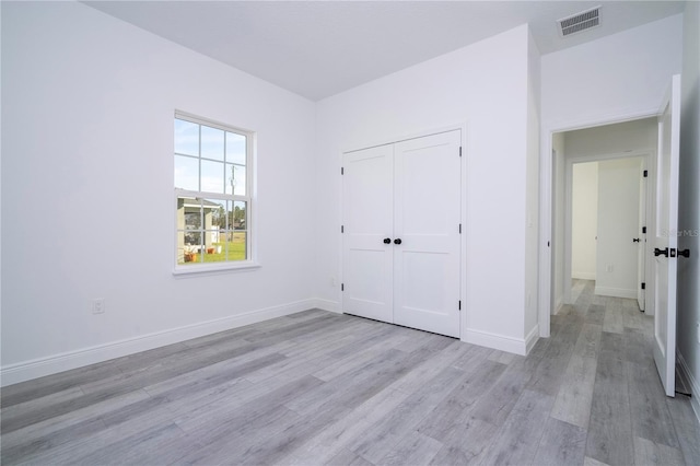 unfurnished bedroom featuring light wood-style flooring, a closet, visible vents, and baseboards