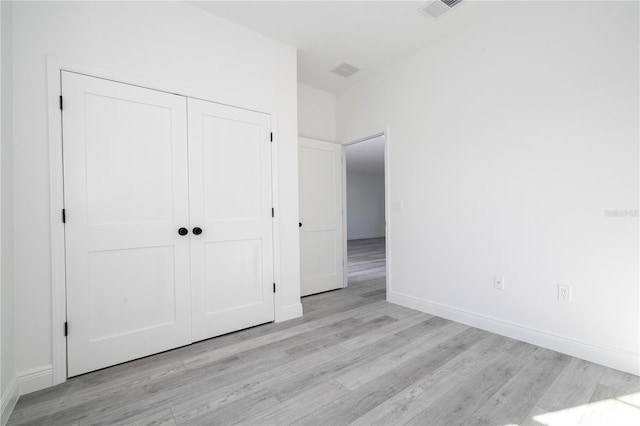 unfurnished bedroom featuring a closet, light wood-type flooring, visible vents, and baseboards