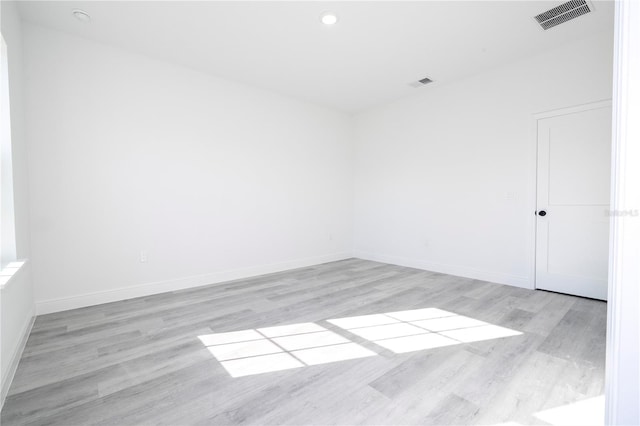 empty room featuring light wood finished floors, visible vents, and baseboards