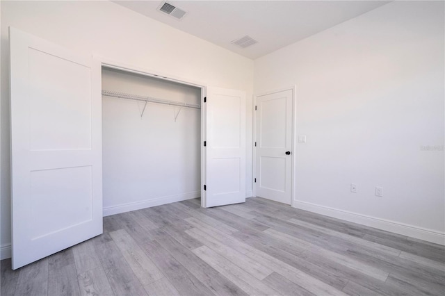 unfurnished bedroom with light wood-type flooring, a closet, visible vents, and baseboards