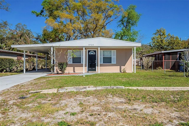 manufactured / mobile home featuring an attached carport, concrete driveway, a front yard, and stucco siding