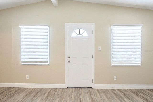 entryway featuring lofted ceiling with beams, wood finished floors, baseboards, and a healthy amount of sunlight