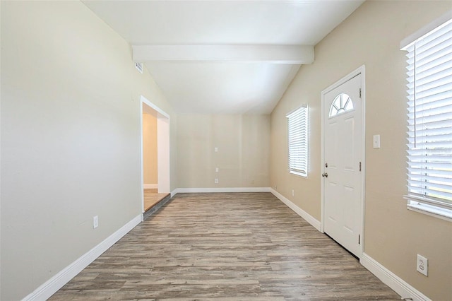 foyer entrance featuring vaulted ceiling with beams, baseboards, and wood finished floors