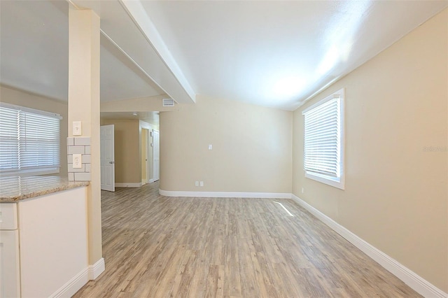 unfurnished living room featuring lofted ceiling with beams, light wood-style floors, and baseboards