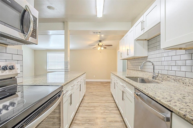 kitchen with light wood finished floors, white cabinets, appliances with stainless steel finishes, and a sink