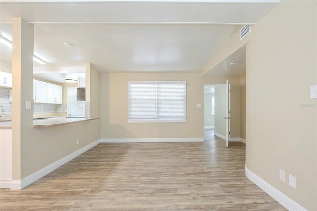 unfurnished living room with light wood-style flooring, baseboards, and visible vents