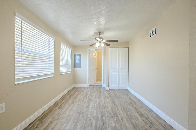 unfurnished bedroom with wood finished floors, baseboards, visible vents, a closet, and a textured ceiling