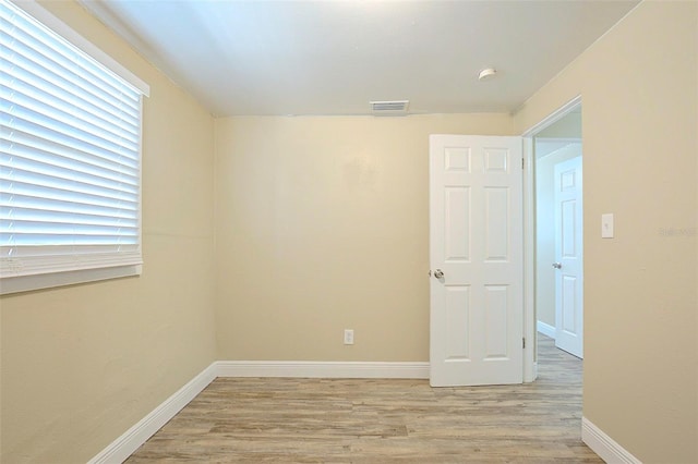 empty room with baseboards, visible vents, and light wood finished floors