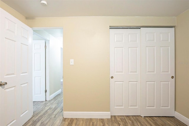 unfurnished bedroom with a closet, light wood-type flooring, and baseboards