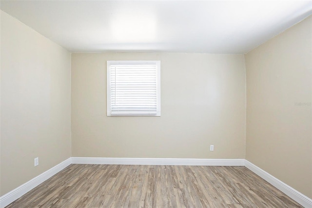 unfurnished room with baseboards and wood finished floors