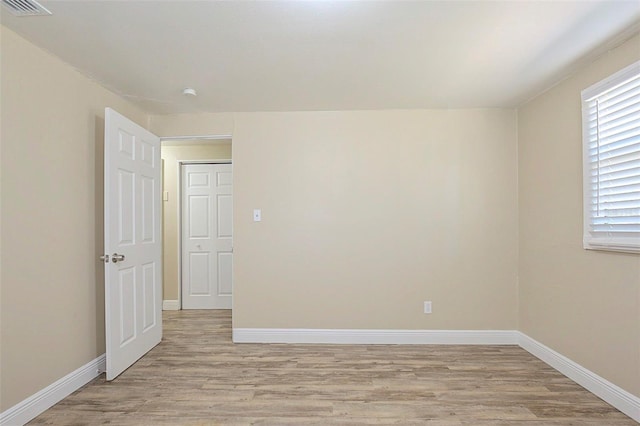 spare room with light wood-style flooring, visible vents, and baseboards