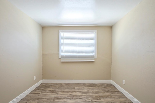 spare room with baseboards and wood finished floors